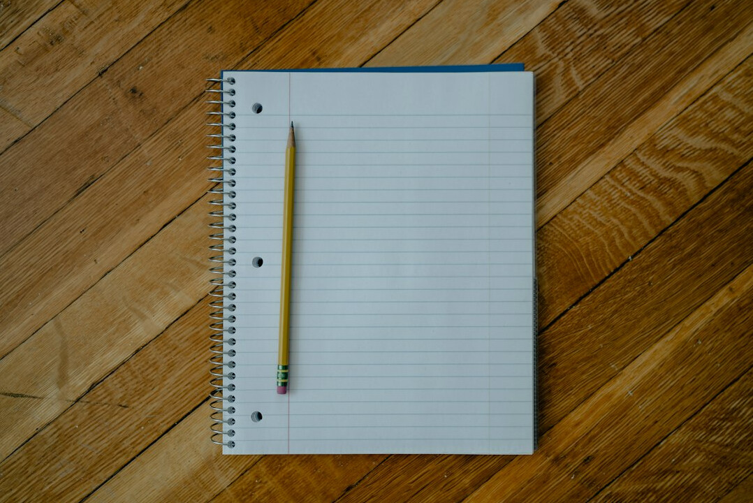 Open notebook with handwritten notes and a pen on a desk